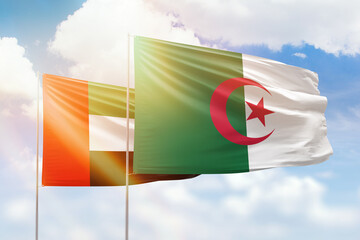 Sunny blue sky and flags of algeria and uae