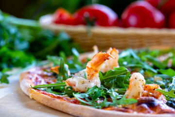 Delicious rustic Italian pizza with grilled Adriatic shrimps, mozzarella, sun dried tomatoes, arugula and parmesan cheese