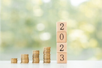 stack of coins on wooden table with new year message 2023 business growth new beginning