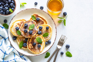 Pancakes with fresh blueberries and honey at white table. Healthy breakfast or dessert. Top view with copy space.