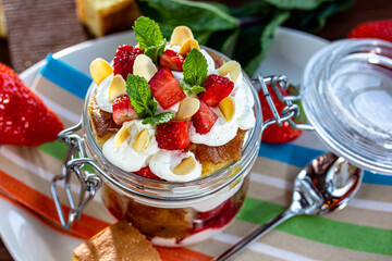 Layered Dessert of chocolate sponge cake, whipped cream or ricotta and fresh strawberries in a glass bowl. Trifle. Delicious gourmet breakfast.