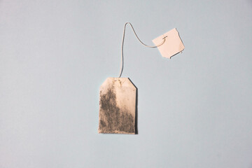 Tea bag with white label on light blue table background. Pastel color. Closeup. Empty place for...