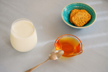 Glass of milk, honey and whole wheat cookies on the table.