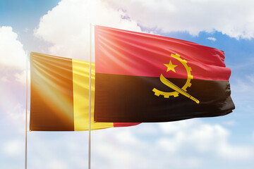 Sunny blue sky and flags of angola and belgium