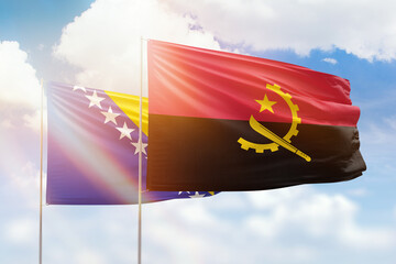 Sunny blue sky and flags of angola and bosnia