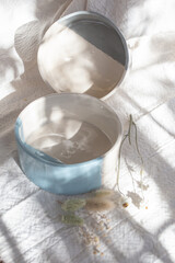 coloured ceramic vessels on white fabric and dried flowers