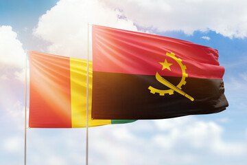 Sunny blue sky and flags of angola and guinea