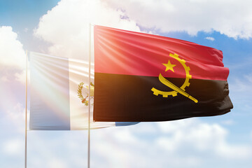 Sunny blue sky and flags of angola and guatemala
