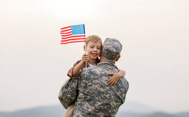 Happy boy son with american flag hugging father came back from US army