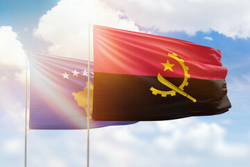 Sunny blue sky and flags of angola and kosovo