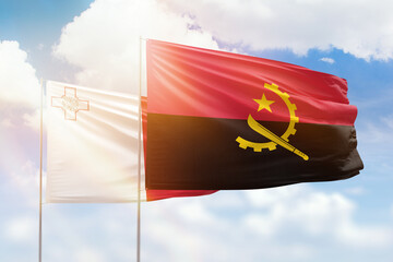 Sunny blue sky and flags of angola and malta