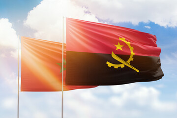 Sunny blue sky and flags of angola and morocco