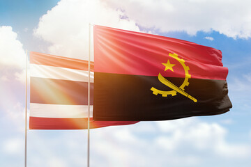 Sunny blue sky and flags of angola and thailand