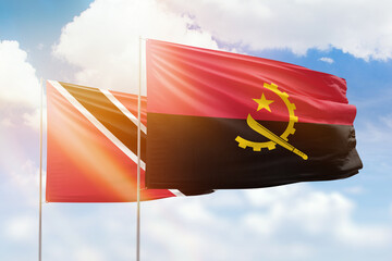 Sunny blue sky and flags of angola and trinidad and tobago