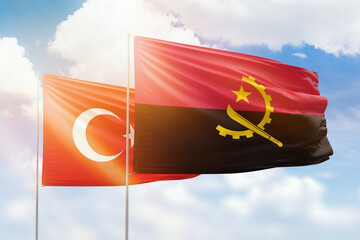 Sunny blue sky and flags of angola and turkey