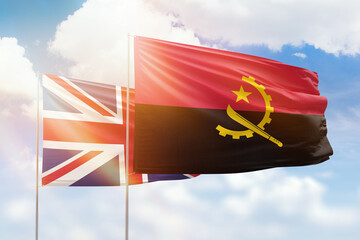 Sunny blue sky and flags of angola and united kingdom