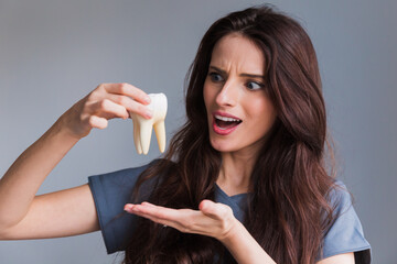 Health dental care concept. Woman hand holding white healthy tooth model. Teeth whitening, dental...