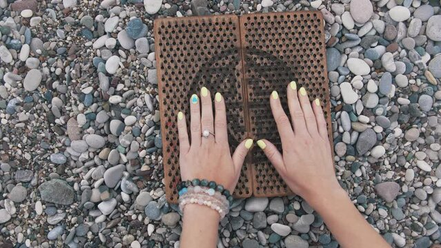 Female hands with painted nails touching the sadhu board on the seashore