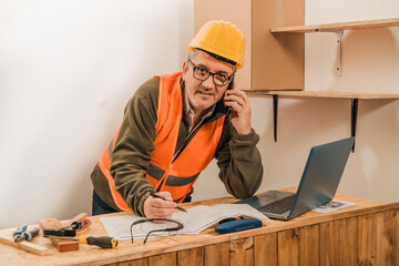 Contractor construction engineer reviewing the development of the work and talking by cell phone with the supplier.