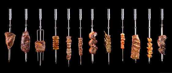 Traditional Brazilian barbecue meats on skewers on a black background - obrazy, fototapety, plakaty