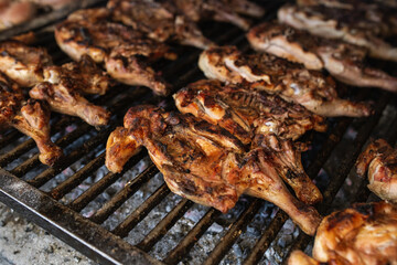 seasoned chickens cooking on the coals on a metal grill