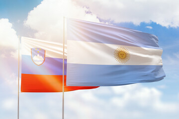 Sunny blue sky and flags of argentina and slovenia