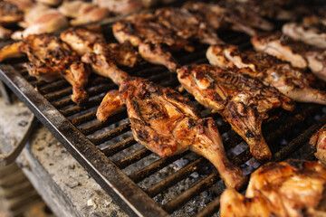 seasoned chickens cooking on the coals on a metal grill