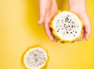 hands holding a dragon fruit on yellow background