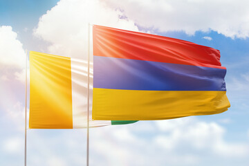 Sunny blue sky and flags of armenia and ivory coast