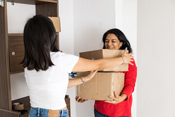 Two women carrying boxes out of an empty room