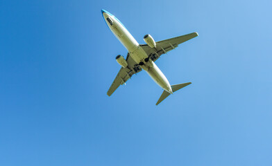 Passenger plane landing overhead over blue sky in the background
