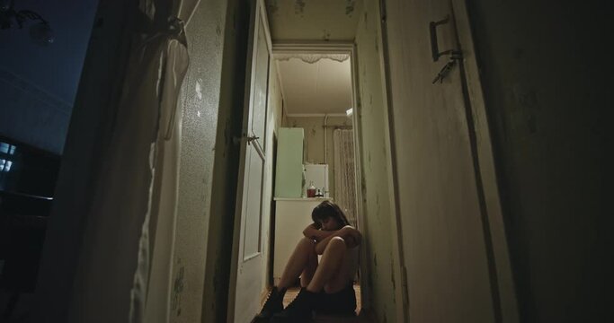 The girl sits on the floor of a Russian communal house and smokes a cigarette