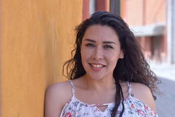 Mujer latina morena bonita sonriente en calle de pueblito 