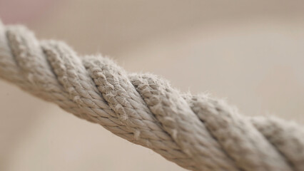 Close-up of part of twisted rope. Action. Macro photography of villi of twisted rope on blurry background. White sports rope with lint