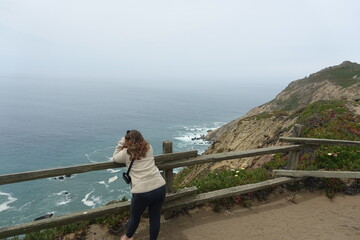 A young woman admiring  scenic view of the rugged northern california coastline in Point Reyes...