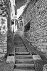 Fototapeta premium Black and white view of an old alley in the village of Assisi (Umbria Region, Central Italy); ancient medieval city, is world famous as birthplace of St. Francis, Italy's christian Patron.