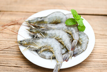 raw shrimp on white plate with mint leaf and wooden background for cooking, close up fresh shrimps or prawns, seafood shelfish