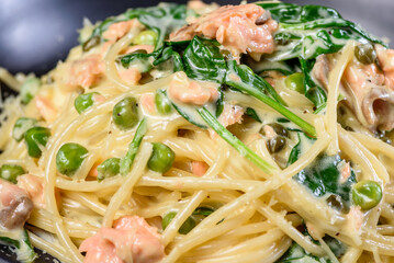 A close view of Salmon Spaghetti in a dark round bowl