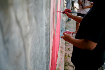 Close up hand of mural artist paint on the street wall