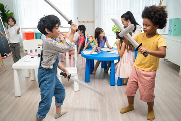 Group of Active mixed race young little kid play sword in schoolroom.