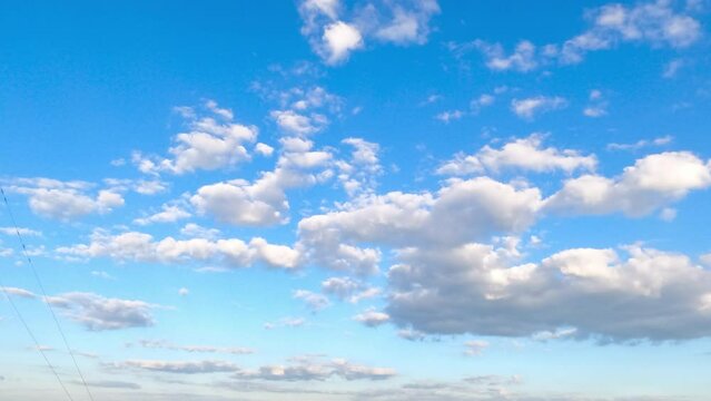 Big and separate little clouds float in the amazing blue sky. Timelapse of light fluffy clouds moving in the horizon.