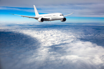 White passenger plane in flight. Aircraft  fly above the clouds.