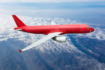 Red passenger plane in flight. Aircraft flies in the sky above the cumulus clouds.