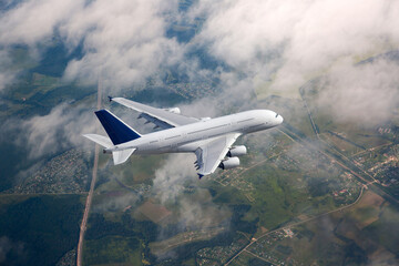 White passenger double decker plane in flight. Aircraft fly high above the clouds.