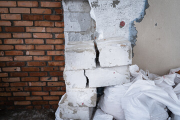 Construction debris on the background of the wall of a private house. Dismantled wall insulation. Cracked concrete block