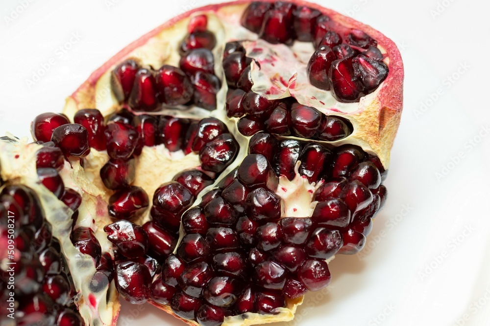 Wall mural broken juicy bright ripe pomegranate on a white background close-up