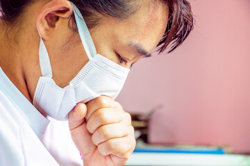 Closeup portrait  Asian lady wearing a face mask and putting a hand on her mouth because of cough and illness. Health care concept.