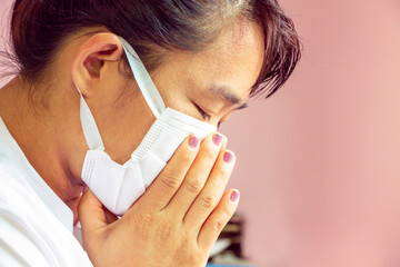 Closeup portrait of Asian lady wearing a face mask and putting a hand on her mouth because cough and illness. Health care concept.
