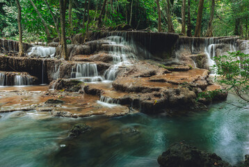 Beautiful waterfall in the tropical jungle at Kanchanaburi, Thailand. Emerald green waters in the forest.