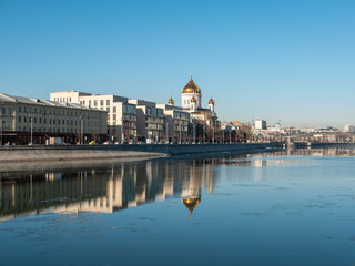 Beautiful view of the embankment of the Muzeon Park and the Cathedral of Christ the Savior against the blue sky. Houses are reflected in the Moscow River. Copy space. Moscow, Russia